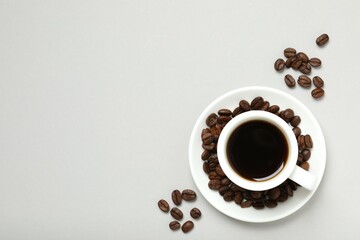 Cup of coffee and coffee beans on gray background