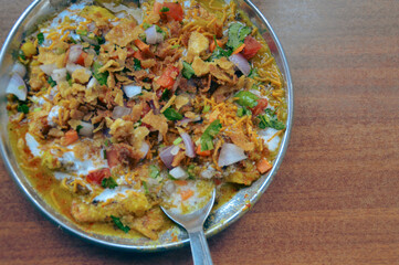 Bhel puri chaat served in a plate with a spoon, showcasing puffed rice, sev, chopped onions, and tomatoes in a vibrant mix. Traditional authentic snack food originating in Mumbai, India