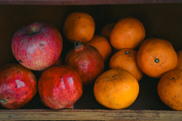 Apples, pomegranates, and oranges on a rustic wooden shop shelf that shows the candid daily life moment and local small business in Pokhara Nepal