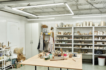 Spacious pottery studio with table and pots.
