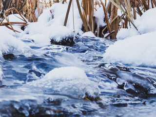 Winter landscape: a frozen stream covered with ice and snow creates an atmosphere of calm and beauty of the cold season