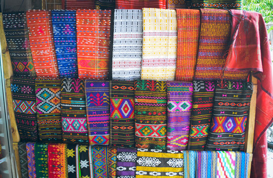 A display rack of colorful traditional woven fabric called Ulos showing the authentic culture and heritage of the Batak indigenous people of Indonesia
