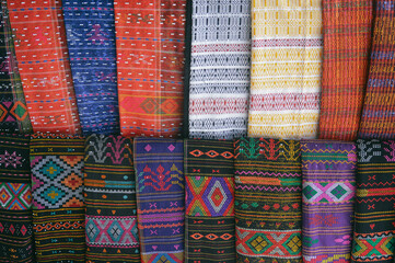 Rows of colorful traditional woven fabric called Ulos sold as souvenirs showing the authentic...