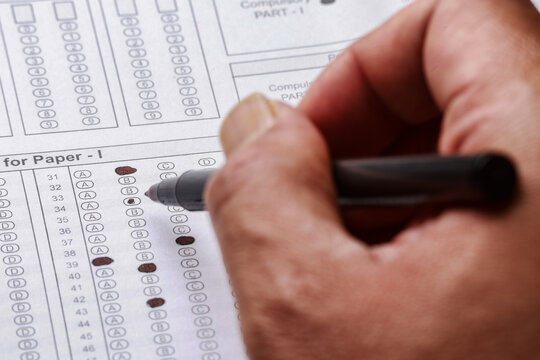 Man is filling OMR sheet handing with pen. Computerized testing, Optical Mark Recognition.Optical exam answer sheet with pen. OMR answering paper for examination