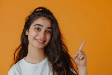 Obraz premium Cheerful Pakistani girl pointing to copy space in studio portrait