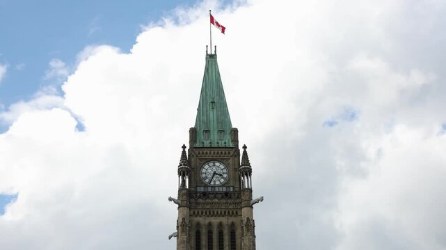 Peace Tower of Canadian Parliament building with flag against the sky in Ottawa, Canada.