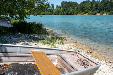 Fluss-Seeufer in Bayern, im Abschnitt ein Fischerboot am steinigen Seeufer, traumhaftes...