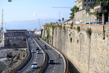 City traffic. Traffic on the elevated road.In the background the equipment of the port of Genoa. Italy