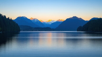 Obraz premium A serene lake with snow-capped mountains in the background. The water is calm and reflective, and the sky is a soft blue.