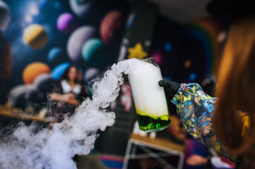 A female children's animator conducts a chemical experiment, experience, show with colored liquid...