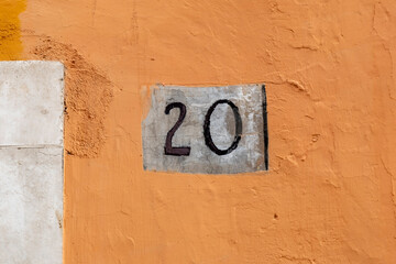 Number twenty on rough panel on plaster wall