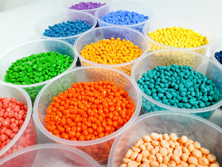 Various colored masterbatch granules in a cup on a white background.Polymer carriers of color pigments in the plastics industry