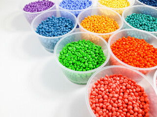 Various colored masterbatch granules in a cup on a white background.Polymer carriers of color pigments in the plastics industry