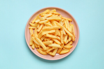 Plate with golden french fries on blue background