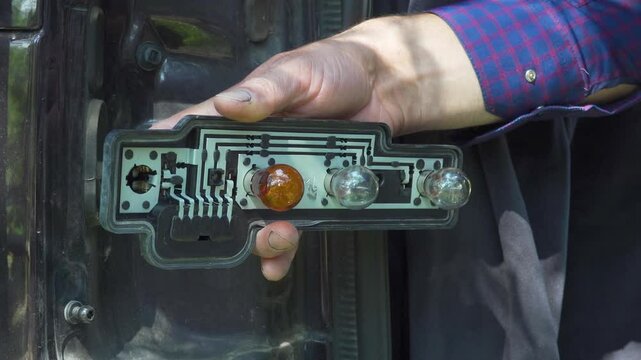 replacement of the lamp in the headlight in the car, a man pulls out a burned-out lamp from a headlight in a car