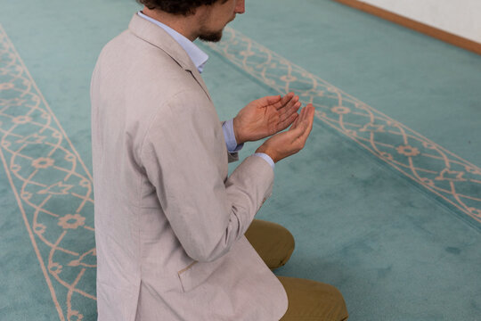 man raising hand in prayer in mosque