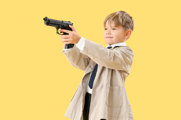 Cute little detective with gun on yellow background. Opposite Day celebration