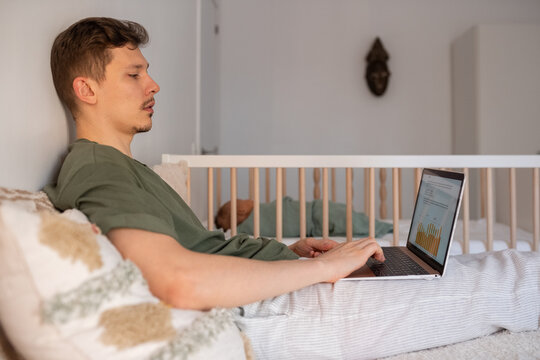 Man working on laptop in bedroom