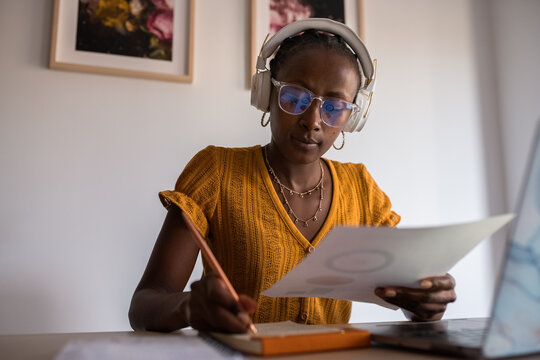 Businesswoman taking notes while studying financial report