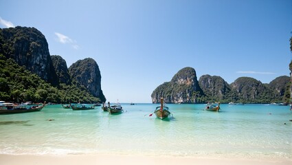 Obraz premium Exotic Thai beach with limestone cliffs clear waters and longtail boats