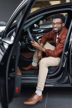 Gentleman posing while sitting in driver seat behind wheel of vehicle