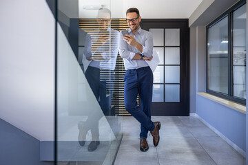 Professional Man Smiling While Using Smartphone in Modern Office