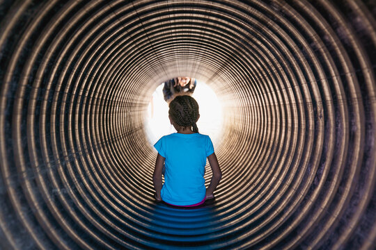 Kindergarten aged child sliding down a metal tube