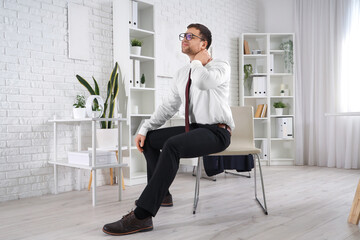 Businessman suffering from neck pain in office