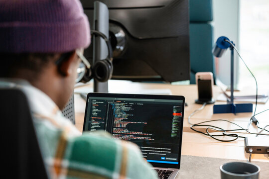 A man is programming on a laptop in the office