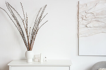 Fototapeta premium Vase with willow branches on commode in light living room