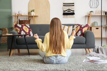 Young woman meditating on floor in living room