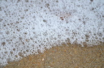Ocean wave bubbles on sandy beach