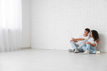 Young happy couple sitting on floor in their new flat