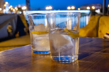 Glasses of cold mineral sparkling water served outdoor with ice cubes in cafe at night in historical Triana district, Sevilla, Spain