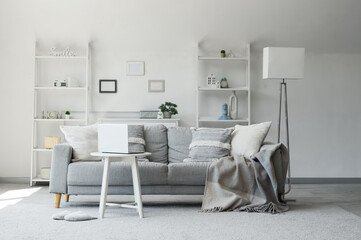 Cozy sofa and coffee table with laptop in living room