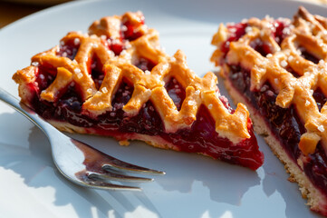 Homemade open sour cherry pie, delicious sweet dessert served in pieces outdoor in garden