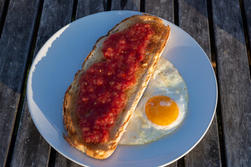 Traditional andalusian breakfast on roof patio with bread toasts, fresh ground tomatoes sauce and olive oil, roasted egg, Sevilla, Andalusia, Spain.