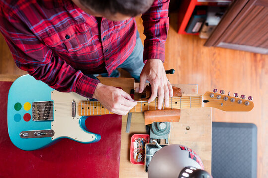 Skilled technician fixing electric guitar