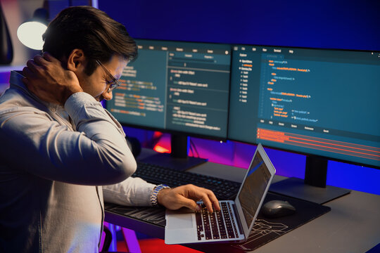 IT developer being tried of overwork on solve problem in error software coding system with sitting to stretch body, concept of programmer working online website database at neon light office. Surmise.