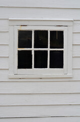 Small antique window with white wooden siding