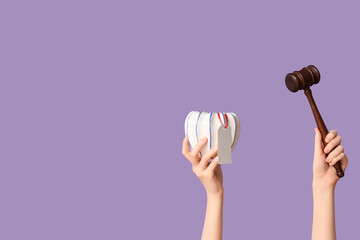 Woman holding auction gavel and antique vase on lilac background