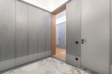 Elegant entrance hall, decorated in gray tones. Light floor tiles. Spacious built-in .wardrobe.