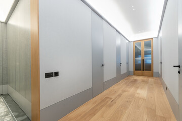 A wide corridor in the apartment. Parquet floor, blue wall decor, bright ceiling .lighting.
