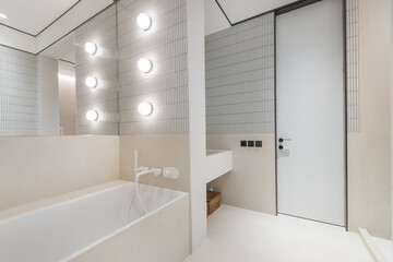 The designer interior of the bathroom, decorated in pastel colors. Panoramic mirror .over the bathroom, white faucet and stylish lamps.