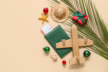 Gift box, palm leaves, passport and wooden airplane on beige background. Christmas vacation concept