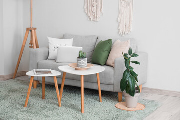 Interior of stylish living room with grey sofa, coffee table and standard lamp near white wall
