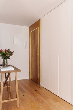 A minimalist hallway with wooden flooring and a wooden entrance door 