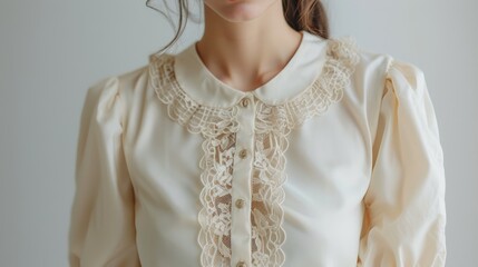 A dainty and elegant creamcolored blouse with billowy lace sleeves and a smooth satin collar perfect for pairing with highwaisted skirts.
