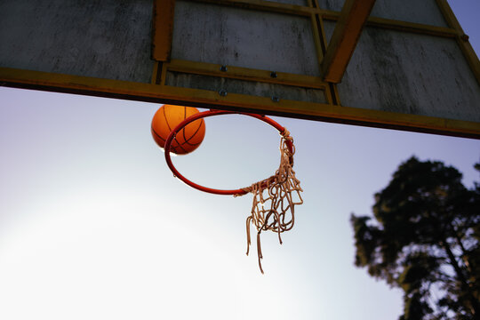Orange basketball going through hoop at sunset in park