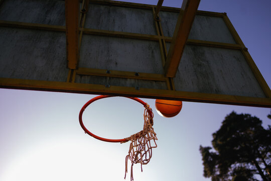 Basketball flying through air towards basket at sunset